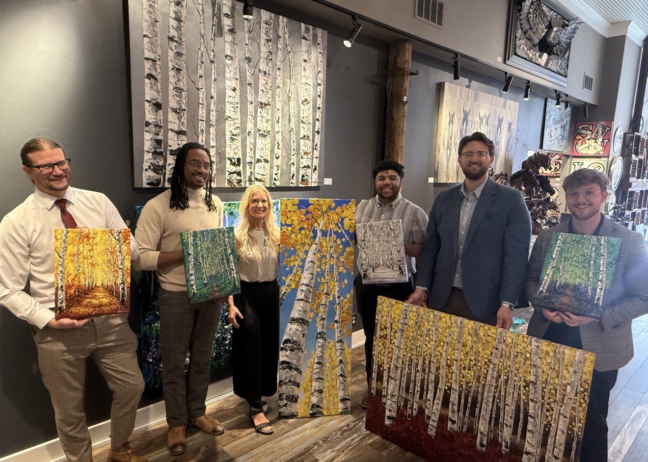 Jennifer Vranes with the Pando Fine Art team, holding birch paintings