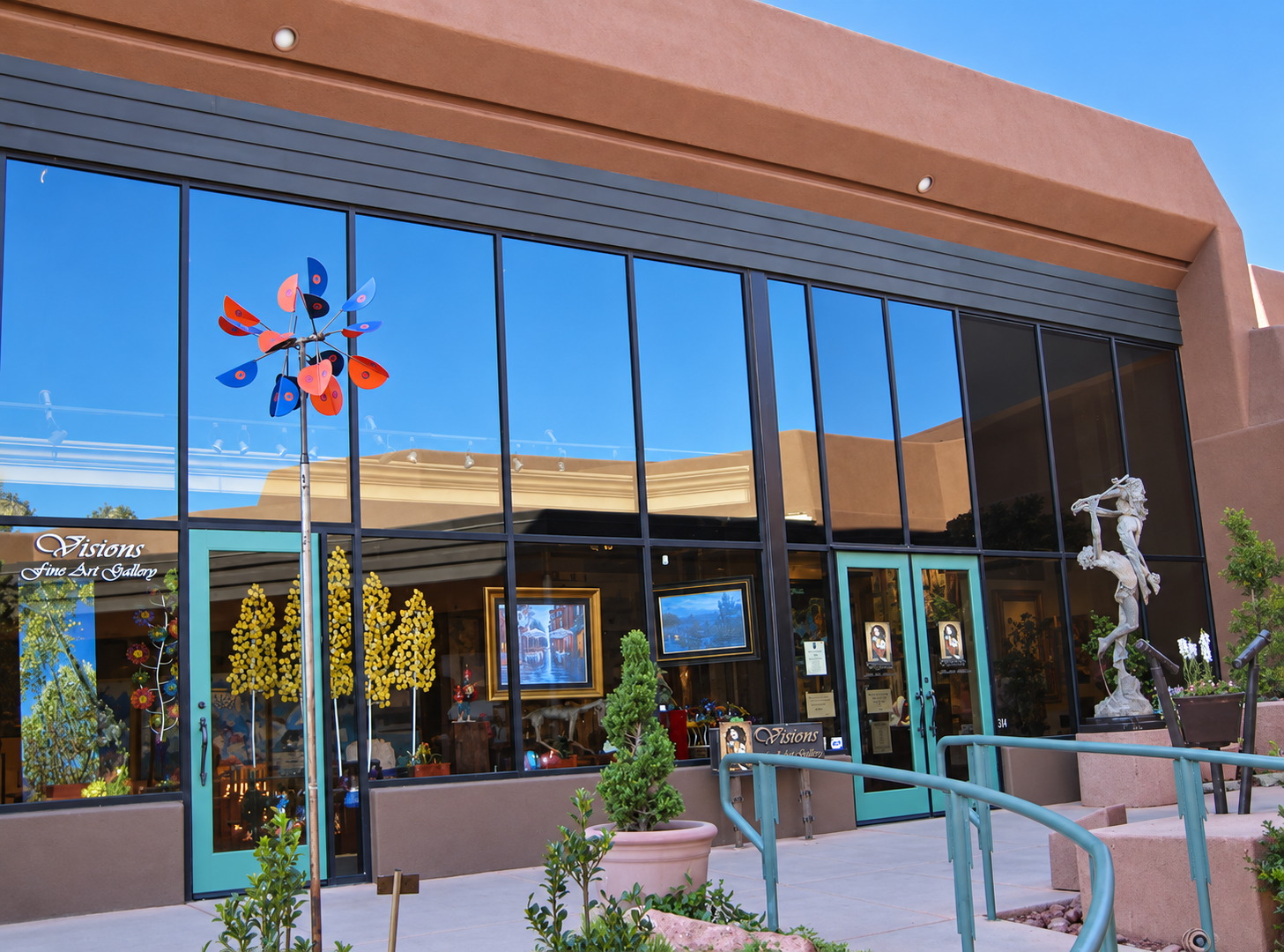 Visions Fine Art Gallery storefront in Sedona, with turquoise doors and a bronze flute player